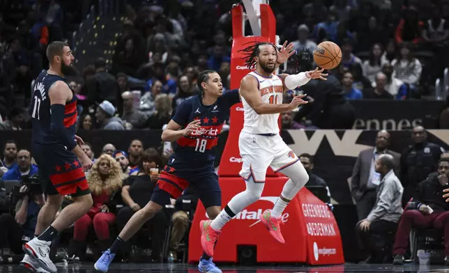 New York Knicks guard Jalen Brunson (11) passes the ball as Washington Wizards forward Kyshawn George (18) defends during the first half of an NBA basketball game, Saturday, Dec. 28, 2024, in Washington. (AP Photo/Terrance Williams)