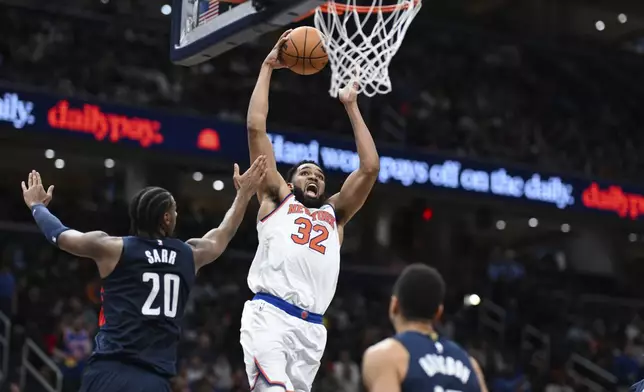 New York Knicks center Karl-Anthony Towns (32) goes to the basket for a dunk over Washington Wizards forward Alexandre Sarr (20) during the second half of an NBA basketball game, Saturday, Dec. 28, 2024, in Washington. (AP Photo/Terrance Williams)