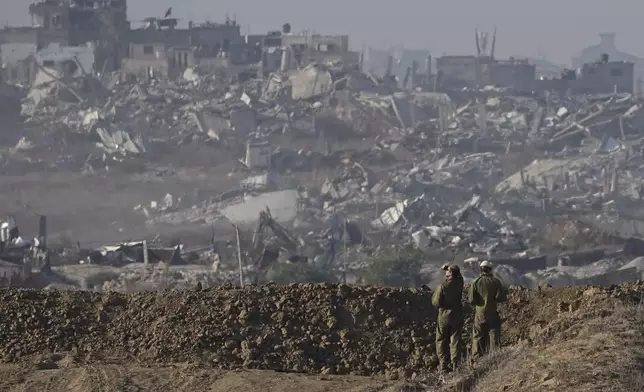 Israeli soldiers look at a destroyed part of Gaza City from their position at the Israel-Gaza border, as seen from southern Israel, Sunday Dec. 1, 2024. (AP Photo/Tsafrir Abayov)