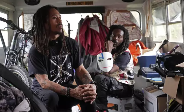 Nate Debos, known by his stage name NaTRILL Dizaster, left, who said he would apply for Benin citizenship, poses with Ay.Yon Michaels, right, of the rap duo Ayakashi Krewe inside an old school bus in New Orleans, Thursday, Dec. 5, 2024. (AP Photo/Gerald Herbert)