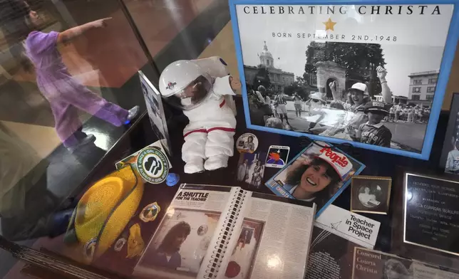 A student passes a selection of memorabilia featuring Christa McAuliffe, NASA's first teacher in space, is displayed at the McAuliffe-Shepard Discovery Center, Monday, Dec. 16, 2024, in Concord, N.H. (AP Photo/Charles Krupa)