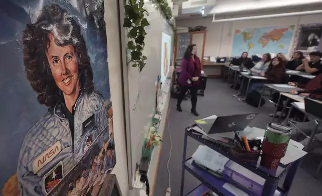 With a poster of NASA's first teacher in space Christa McAuliffe displayed on the wall, teacher Kimberly Bleier instructs her students in one of classrooms where McAuliffe taught at Concord High School, Monday, Dec. 16, 2024, in Concord, N.H. (AP Photo/Charles Krupa)