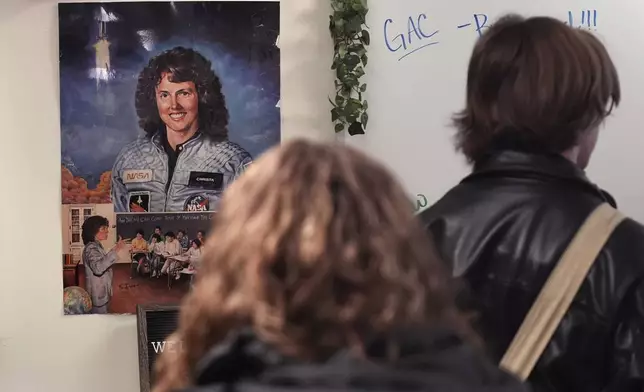 With a poster of NASA's first teacher in space Christa McAuliffe displayed on the wall, students head to their next period class from one of classrooms where McAuliffe taught at Concord High School, Monday, Dec. 16, 2024, in Concord, N.H. (AP Photo/Charles Krupa)