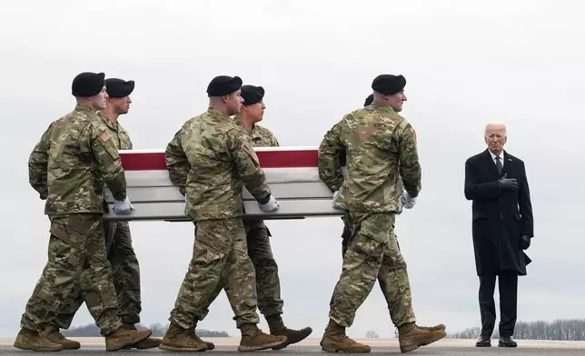 FILE - President Joe Biden, right, stands as an Army carry team moves the transfer case containing the remains of U.S. Army Sgt. Kennedy Ladon Sanders, 24, of Waycross, Ga., at Dover Air Force Base, Del., Friday, Feb. 2, 2024, after Sanders was killed in a drone attack in Jordan on Jan. 28. (AP Photo/Matt Rourke, File)