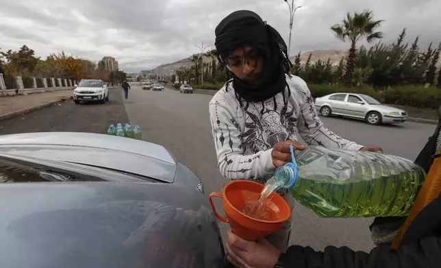 A street vendor fills up a car's tank with gasoline on a road in Damascus, Syria, Saturday, Dec. 28, 2024. (AP Photo/Omar Sanadiki)