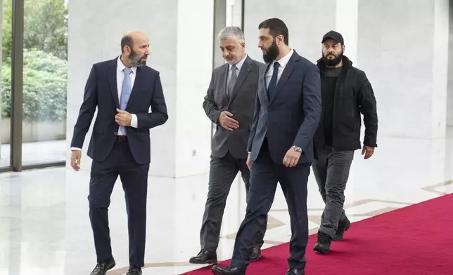 Syria's de facto leader Ahmad al-Sharaa, foreground, formerly known as Abu Mohammed al-Golani, walks in the presidential palace ahead of his meeting with Walid Ellafi, Libyan minister of state for communication and political affairs, in Damascus, Saturday, Dec. 28, 2024. (AP Photo/Mosa'ab Elshamy)