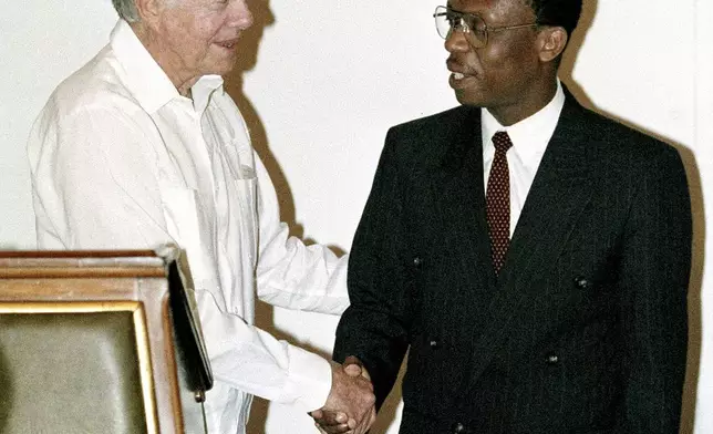 FILE - Former President Jimmy Carter shakes hands with Haitian President Jean-Bertrand Aristide at the Presidential Palace in Port-au-Prince in Haiti, Feb. 23, 1995. (AP Photo/Andrew Innerarity, File)