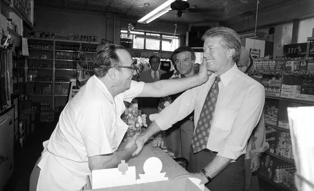 FILE - Democratic presidential candidate Jimmy Carter gets a pinch on the cheek as he greets Charlie Lanzaro, left, at a Queens, N.Y., delicatessen, Aug. 31, 1976. Carter had just arrived in New York on a campaign swing. (AP Photo/Peter Bregg, File)