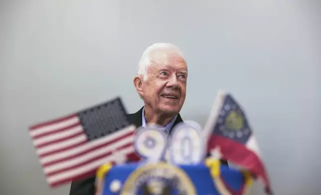 FILE - Former President Jimmy Carter stands behind his birthday cake during his 90th birthday celebration held at Georgia Southwestern University, Oct. 4, 2014, in Americus, Ga. (AP Photo/Branden Camp, File)