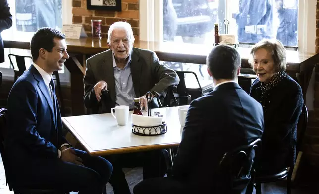 FILE - Democratic presidential candidate and former South Bend, Ind., mayor, Pete Buttigieg, left, and his husband Chasten Buttigieg, second from the right, meet with former President Jimmy Carter and former first lady Rosalynn Carter at the Buffalo Cafe in Plains, Ga., March 1, 2020. (AP Photo/Matt Rourke, File)