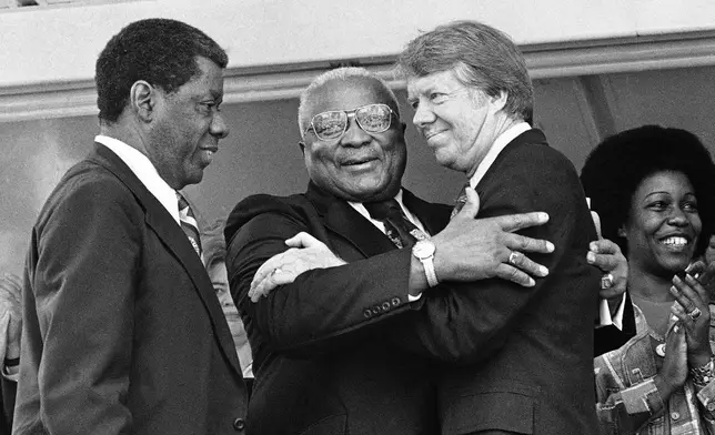 FILE - The Rev. Dr. Martin Luther King Sr., center, and Democratic presidential candidate Jimmy Carter, right, embrace during a campaign rally where King declared, "I love and believe in him," in Atlanta, April 13, 1976. In a prepared speech read by Atlanta businessman Jesse Hill, left, King said Carter has been for equal justice when it wasn't an easy thing to be for in South Georgia. (AP Photo, File)