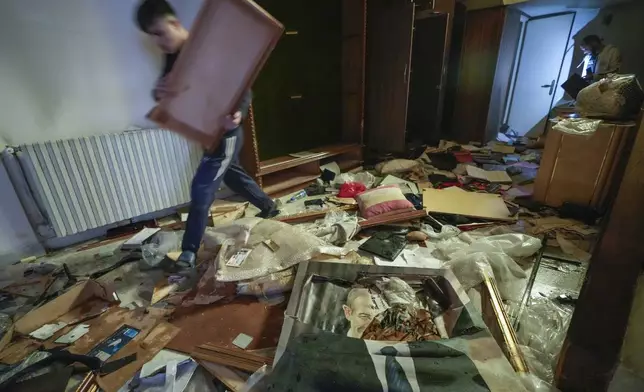 A man walks by a broken portrait of the late Syrian President Hafez Assad as people search for belongings in the ransacked private residence of Syrian President Bashar Assad in the Malkeh district of Damascus, Syria, on Sunday, Dec. 8, 2024. (AP Photo/Hussein Malla)