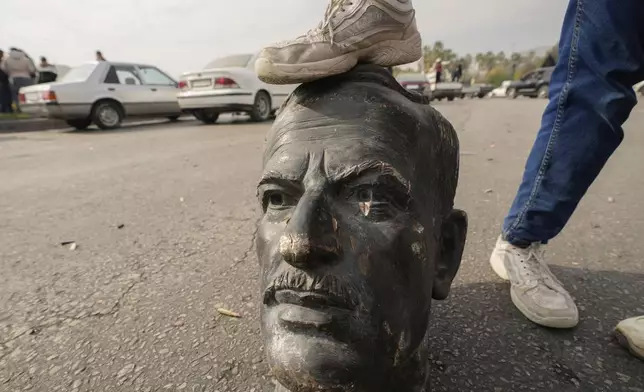 An opposition fighter steps on a broken bust of the late Syrian President Hafez Assad in Damascus, Syria, Sunday Dec. 8, 2024. (AP Photo/Hussein Malla)