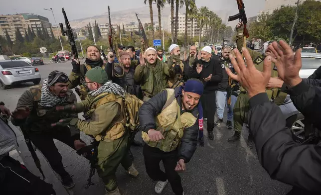 Opposition fighters celebrate in Damascus, Syria, Sunday Dec. 8, 2024. (AP Photo/Hussein Malla)