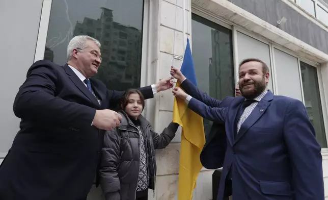 CORRECTS ID Ukrainian Foreign Minister Andrii Sybiha, left, and Honorary Consul General Tamer Altounsi, right, pose for a picture next to the Ukrainian flag at the Ukrainian consulate in Damascus, Syria, Monday, Dec. 30, 2024. (AP Photo/Omar Sanadiki)