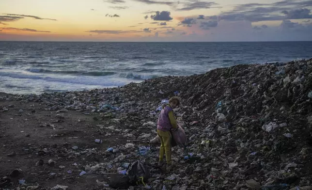 A girl searches for cardboard in the trash to make a fire, near a tent camp for displaced Palestinians by the sea in Deir al-Balah, central Gaza Strip, Monday, Dec. 30, 2024.