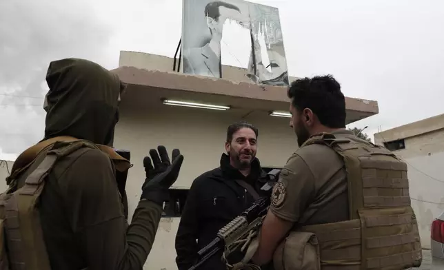 A member of Bashar Assad's army, or a pro-government militia, talks to members of the security forces of the newly formed Syrian government as he takes part in an "identification and reconciliation" process in Damascus, Syria, Monday, Dec. 30, 2024. (AP Photo/Omar Sanadiki)