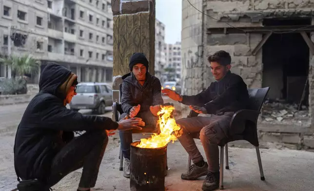 Boys warm up next to a fire on a cold day in Douma, on the outskirts of Damascus, Syria, Sunday, Dec. 29, 2024 (AP Photo/Mosa'ab Elshamy)