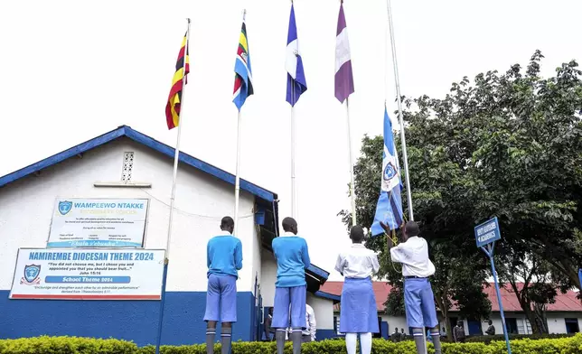 Students lower flags at Wampewo Ntakke Secondary School in Kawempe tula village, Kampala, Uganda on Nov. 4, 2024. (AP Photo/Hajarah Nalwadda)