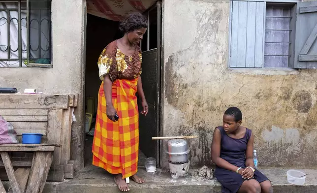 Justine Nangero, left, prepare a meal with her 11-year-old daughter, right, at their home in Kawempe tula village, Kampala, Uganda on Nov. 11, 2024. (AP Photo/Hajarah Nalwadda)