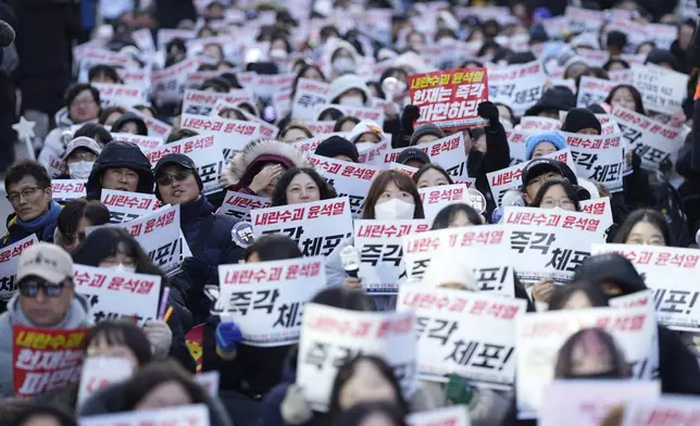 Participants shout slogans during a rally calling on the Constitutional Court to dismiss the President Yoon Suk Yeol in Seoul, South Korea, Sunday, Dec. 15, 2024. The signs read "Immediately arrest." (AP Photo/Lee Jin-man)