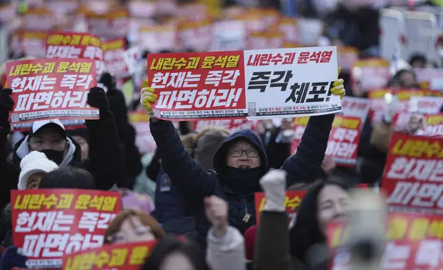 Participants shout slogans during a rally calling on the Constitutional Court to dismiss the President Yoon Suk Yeol, in Seoul, South Korea, Sunday, Dec. 15, 2024. The signs read "Immediately arrest." (AP Photo/Lee Jin-man)