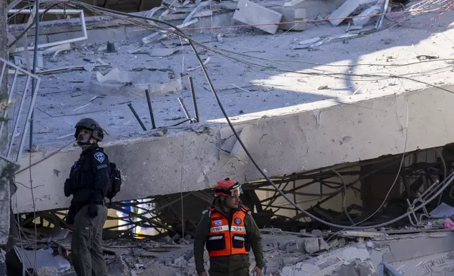 An officer from the home front command military unit and a policeman examine the damage after a large piece of shrapnel from Houthi missile collapsed a school building in Ramat Gan, a suburb of Tel Aviv, Israel, Thursday, Dec. 19, 2024. (AP Photo/Ariel Schalit)