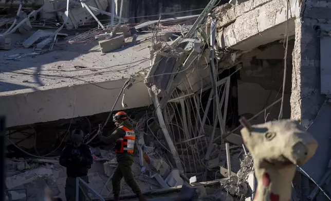 An officer from the home front command military unit examines the damage after a large piece of shrapnel from Houthi missile collapsed a school building in Ramat Gan, a suburb of Tel Aviv, Israel, Thursday, Dec. 19, 2024. (AP Photo/Ariel Schalit)