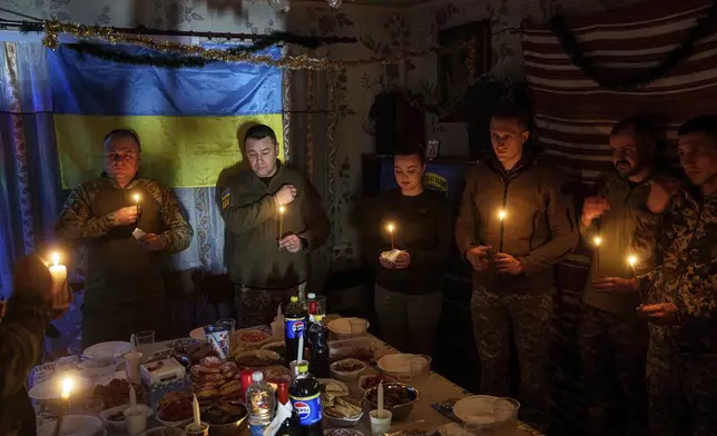 Ukrainian servicemen of 117th Separate Heavy Mechanized Brigade pray before a Christmas dinner on Pokrovsk direction, Donetsk region, Ukraine, Tuesday, Dec. 24, 2024. (AP Photo/Evgeniy Maloletka)