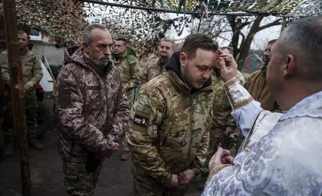 Military chaplain Yurii of 24th Mechanized Brigade blesses Ukrainian servicemen during Christmas near the frontline town of Chasiv Yar, Donetsk region, Ukraine, Wednesday Dec. 25, 2024. (AP Photo/Evgeniy Maloletka)