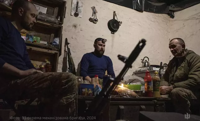 In this photo provided by Ukraine's 33rd Mechanised Brigade press service, servicemen prepare a festive dinner on Christmas Eve in a shelter on the frontline in the Dnipropetrovsk region, Ukraine, Tuesday, Dec. 24, 2024. (Volodymyr Petrov/Ukraine's 33rd Mechanised Brigade via AP)