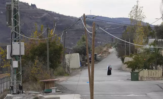 A woman holds her child near the so-called Alpha Line that separates the Israeli-annexed Golan Heights from Syria, in the town of Majdal Shams, Wednesday, Dec. 11, 2024. (AP Photo/Matias Delacroix)