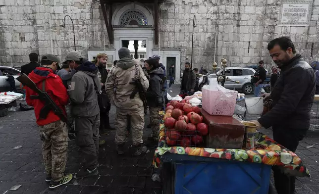 Opposition fighters gather outside the 7th century Umayyad Mosque in Damascus, Syria, Wednesday, Dec. 11, 2024. (AP Photo/Omar Sanadiki)