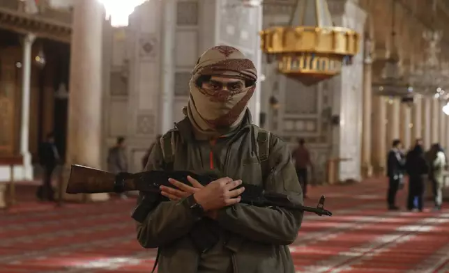 An opposition fighter poses for a photograph inside the 7th century Umayyad Mosque in Damascus, Syria, Wednesday, Dec. 11, 2024. (AP Photo/Omar Sanadiki)