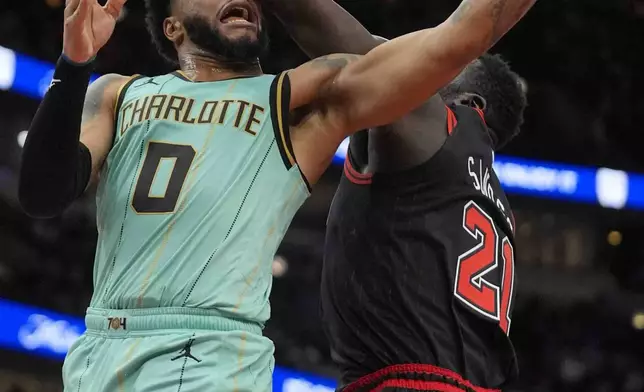 Charlotte Hornets forward Miles Bridges, left, makes a basket despite a block-attempt by Chicago Bulls center Adama Sanogo, right, during the first half of an NBA basketball game Friday, Dec. 13, 2024, in Chicago. (AP Photo/Erin Hooley)