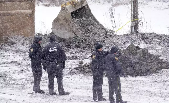 Law enforcement members watch as rescue workers continue to search, Thursday, Dec. 5, 2024, for Elizabeth Pollard, who is believed to have disappeared in a sinkhole while looking for her cat, in Marguerite, Pa. (AP Photo/Matt Freed)