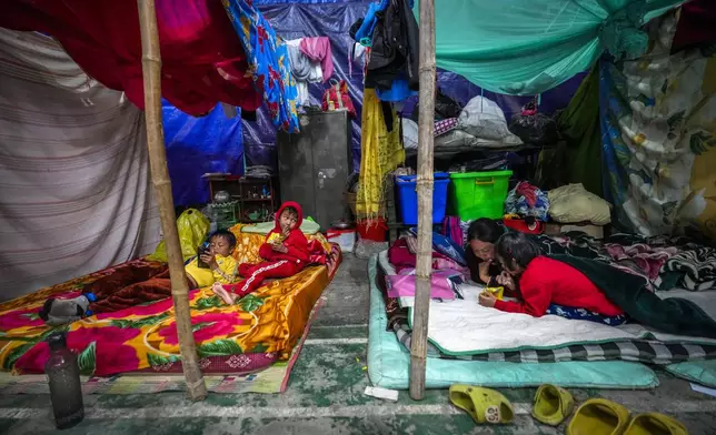 A Meitei woman and children take rest in a relief camp in Imphal, Manipur, Monday, Dec. 16, 2024. (AP Photo/Anupam Nath)