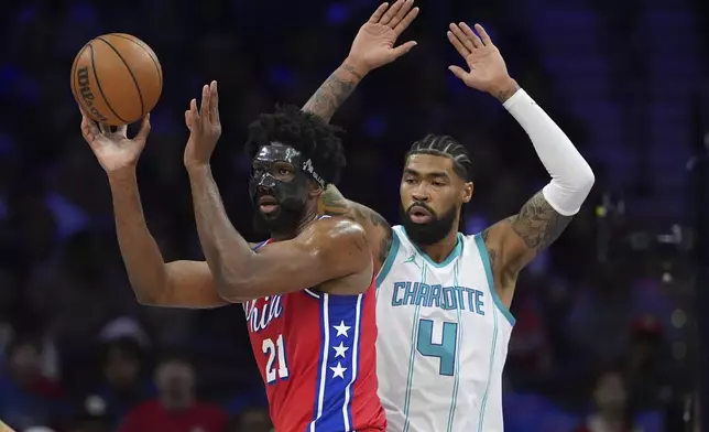 Philadelphia 76ers' Joel Embiid, left, tries to pass against Charlotte Hornets' Nick Richards during the first half of an NBA basketball game, Friday, Dec. 20, 2024, in Philadelphia. (AP Photo/Matt Slocum)