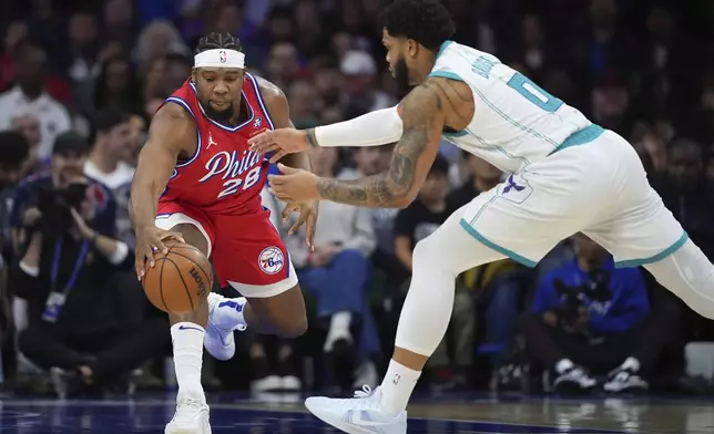 Philadelphia 76ers' Guerschon Yabusele, left, and Charlotte Hornets' Miles Bridges reach for a loose ball during the first half of an NBA basketball game, Friday, Dec. 20, 2024, in Philadelphia. (AP Photo/Matt Slocum)