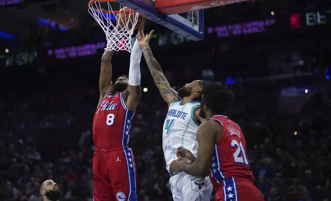 Philadelphia 76ers' Paul George (8) reaches for a rebound against Charlotte Hornets' Nick Richards (4) during the first half of an NBA basketball game, Friday, Dec. 20, 2024, in Philadelphia. (AP Photo/Matt Slocum)