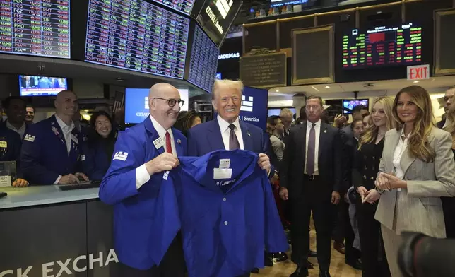 President-elect Donald Trump is handed a coat by trader Peter Giacchi, as he walks the floor of the New York Stock Exchange, Thursday, Dec. 12, 2024, in New York. (AP Photo/Alex Brandon)