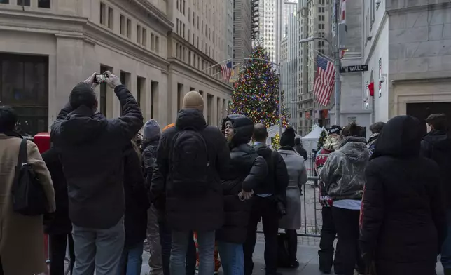 People stand outside the New York Stock Exchange, Thursday, Dec. 12, 2024, in New York. (AP Photo/Julia Demaree Nikhinson)