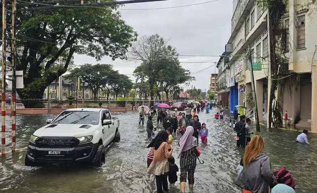 Residents walk on a flooded street after heavy monsoon rains in downtown Kota Bharu, Kelantan, Malaysia, Friday, Nov. 29, 2024. (AP Photo/Loo Kok Chong)