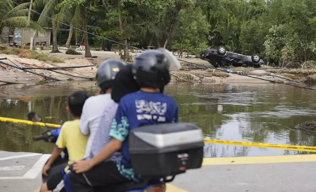 Motorists survey the damage caused by a flood in Tumpat, on the outskirts of Kota Bahru in Kelantan state on the east coast of Malaysia, Tuesday, Dec. 3, 2024. (AP Photo/Vincent Thian)