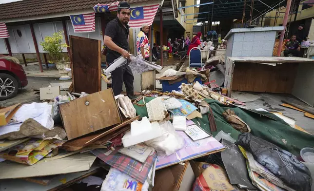 A man sorts items removed from a school affected by a flood in Tumpat, on the outskirts of Kota Bahru, Malaysia, Tuesday, Dec. 3, 2024. (AP Photo/Vincent Thian)