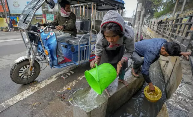 People collect water from an open drain in Guwahati, India, March 22, 2024. (AP Photo/Anupam Nath)