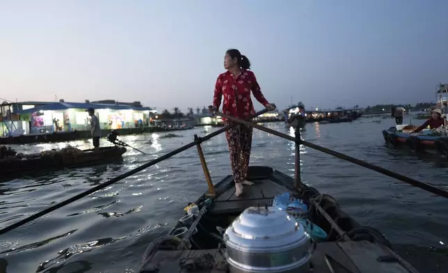 Nguyen Thi Thuy, a vendor who sells steamed buns on a floating market, paddles her boat in Can Tho, Vietnam, Jan. 17, 2024. (AP Photo/Jae C. Hong)