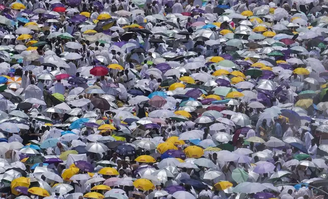 Pilgrims use umbrellas to shield themselves from the sun as they gather outside Nimrah Mosque to offer noon prayers in Arafat, during the annual Hajj, near the holy city of Mecca, Saudi Arabia, June 15, 2024. (AP Photo/Rafiq Maqbool)