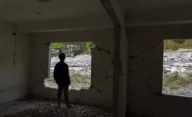 A man gazes out from an abandoned house in Melamchi, Nepal, Sept. 15, 2024, damaged by floods in 2021. (AP Photo/Niranjan Shrestha)