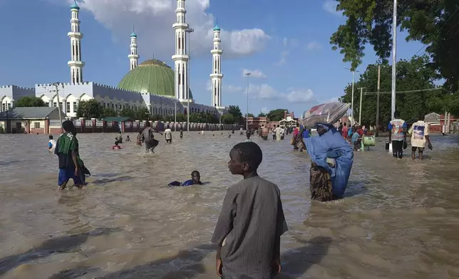 People walk through floodwaters following a dam collapse in Maiduguri, Nigeria, Sept 10, 2024. (AP Photos/ Joshua Olatunji)